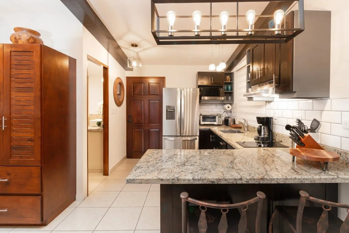 A kitchen with a large island, dark cabinets, and stainless steel appliances.