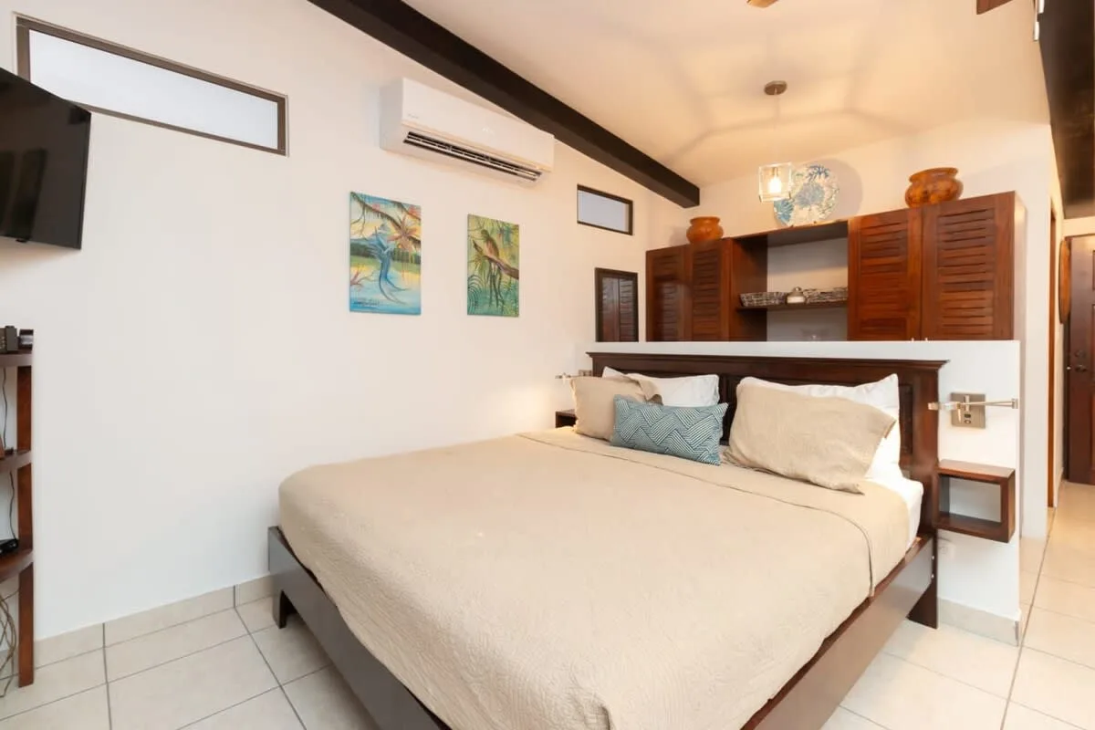 A bedroom with a large bed, wall art, and wooden cabinets.