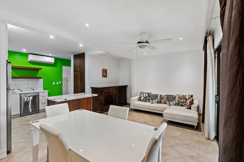 Una sala-comedor abierta con una mesa blanca y asientos.