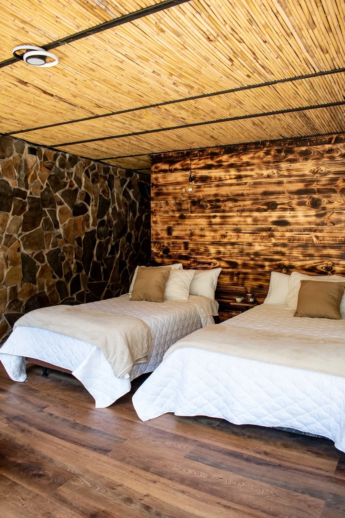 A bedroom with two beds, stone walls, and a wood-paneled wall.