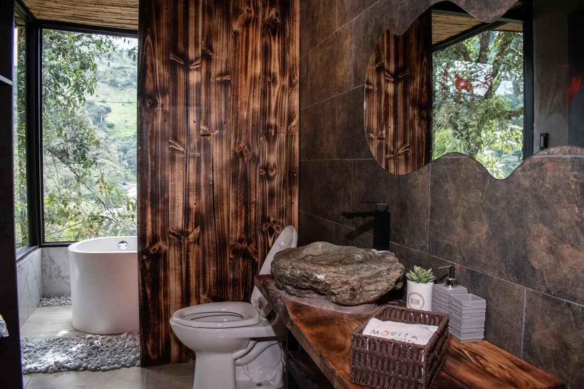 A bathroom with a freestanding tub, toilet, and stone vessel sink.