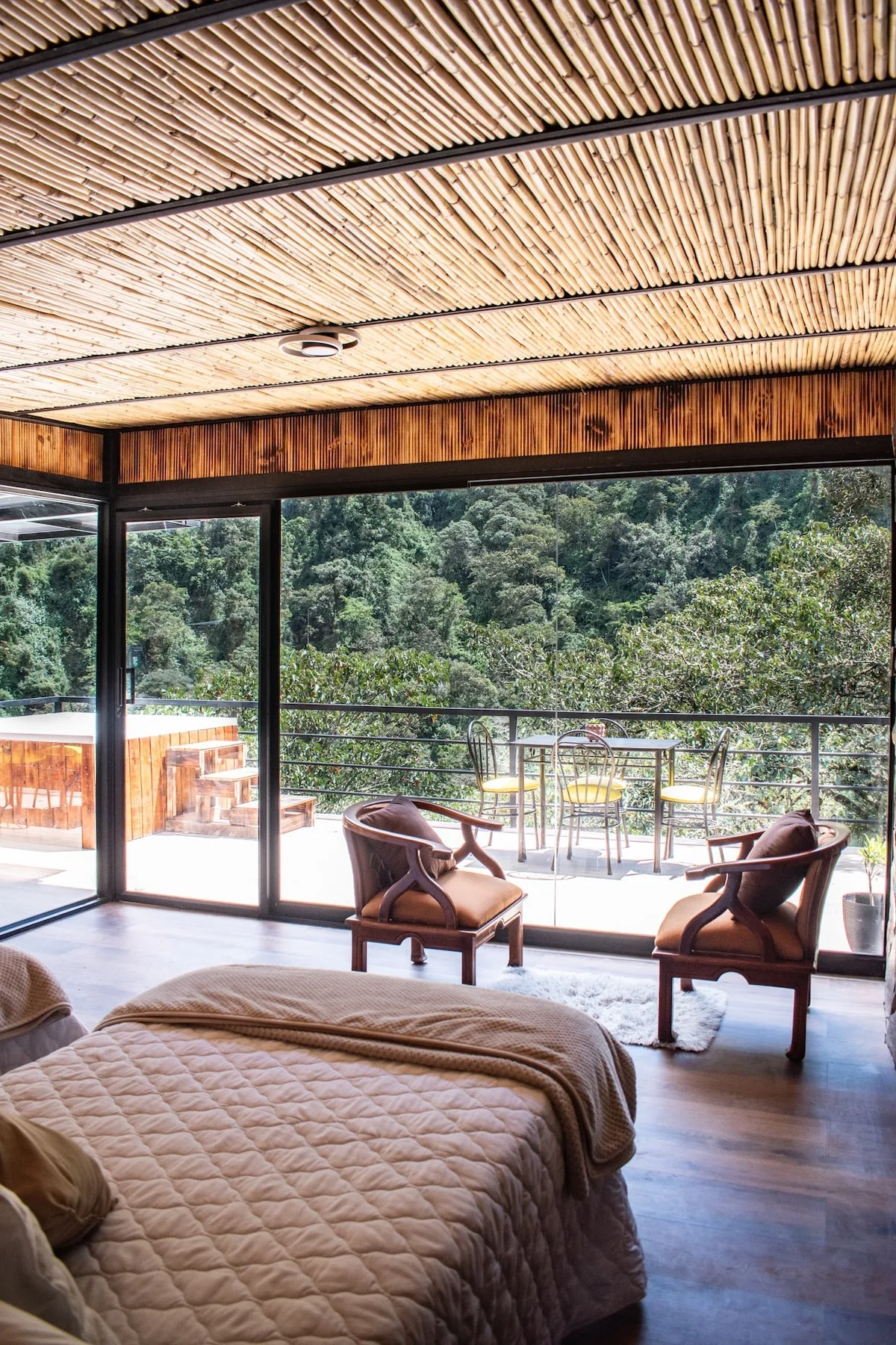 A bedroom opens onto a furnished terrace with forest views.