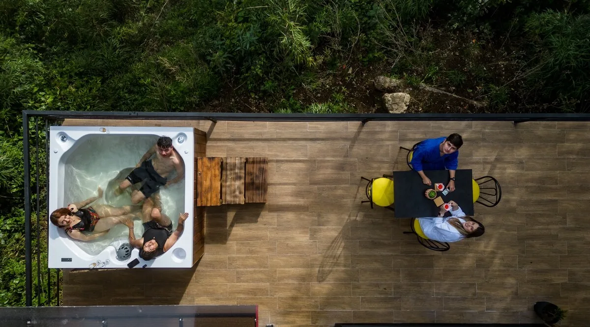 An outdoor deck with a hot tub and a small dining table.