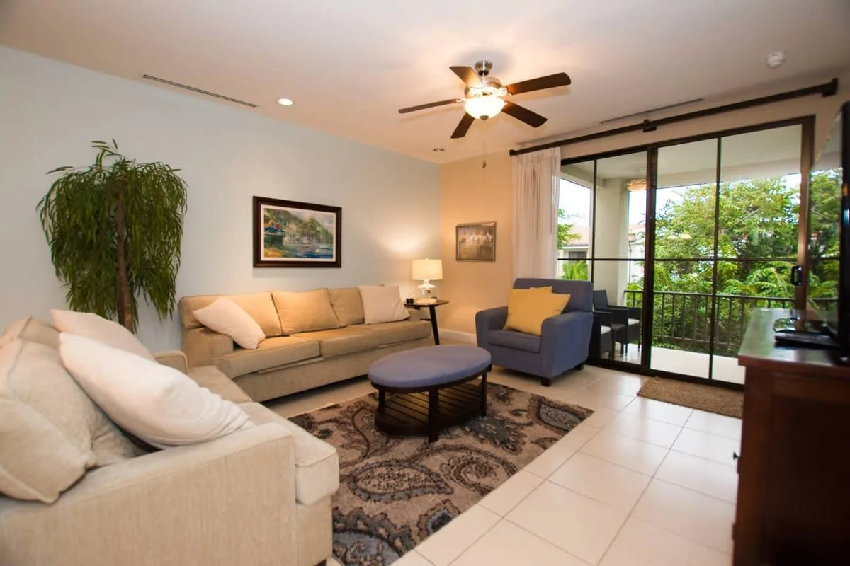 A living room with cushioned seating, a coffee table, and large glass doors.