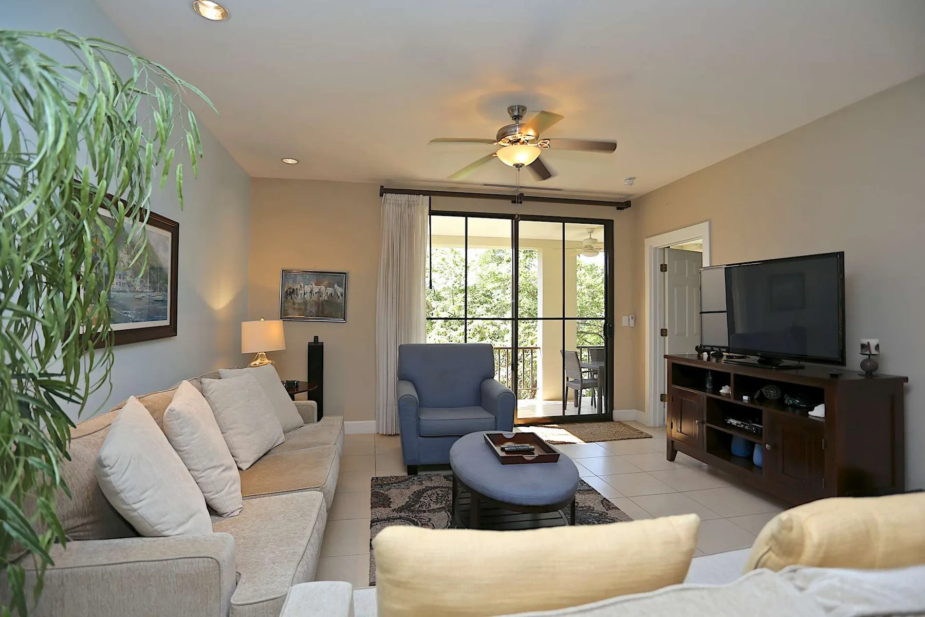 A living room with seating, a television, and glass doors opening to a patio.