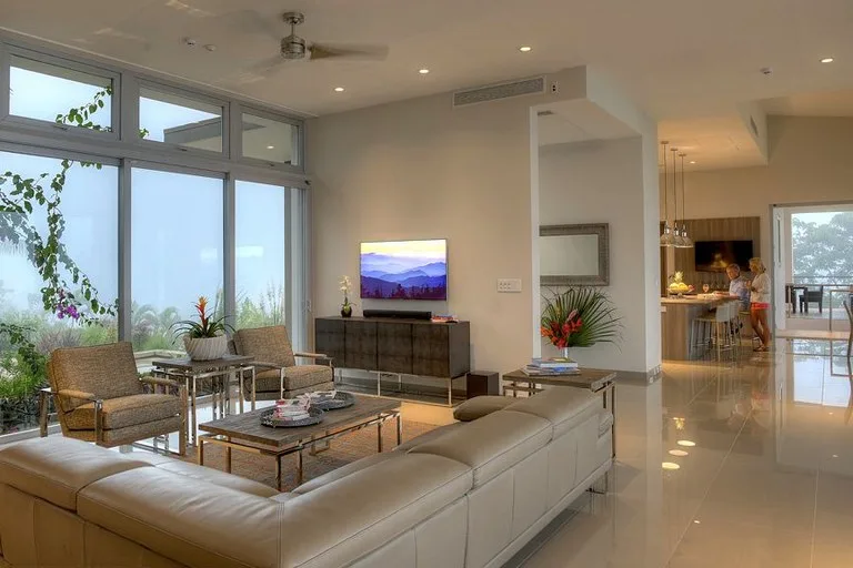 Una luminosa sala de estar diáfana con grandes ventanas, asientos y comedor.