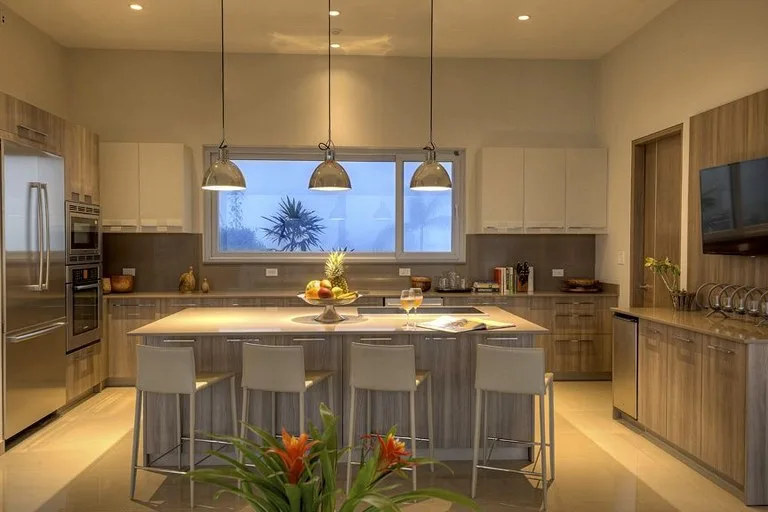 Cocina con una isla central, asientos y lámparas colgantes.