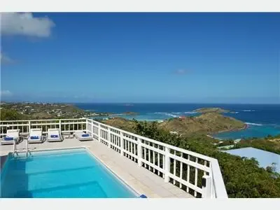 Una piscina en la azotea ofrece vistas de un paisaje costero y el océano.