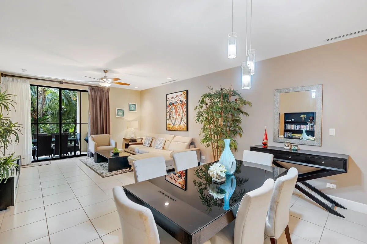 Una sala de estar y comedor luminosa con una mesa de vidrio y asientos.