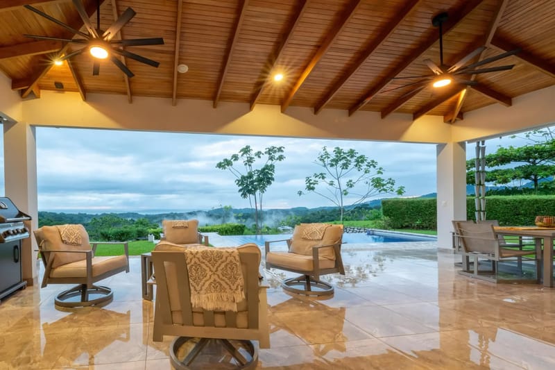 Casa Hacienda Jaguar · 9. The covered outdoor terrace features a high wood-paneled ceiling, comfortable seating, and an outdoor dining area, all opening to an infinity pool with expansive jungle and ocean views.