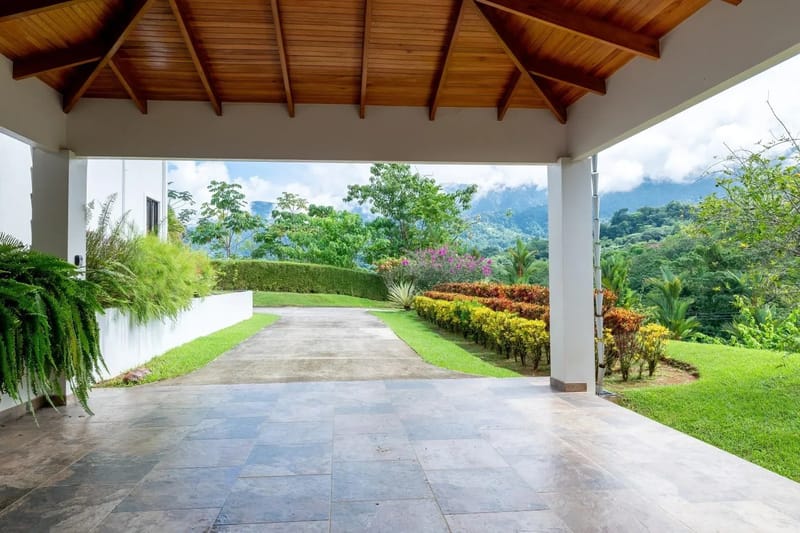 Casa Hacienda Jaguar · 38. A covered entrance features a vaulted wooden ceiling, tiled floor, and open views of tropical landscaping and distant jungle-covered mountains.