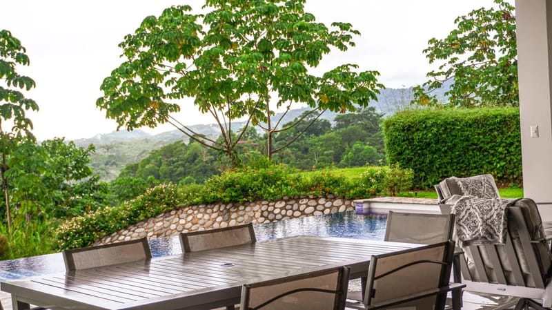Casa Hacienda Jaguar · 7. A covered outdoor dining area next to an infinity pool frames views of dense jungle and rolling mountains, bathed in natural light.