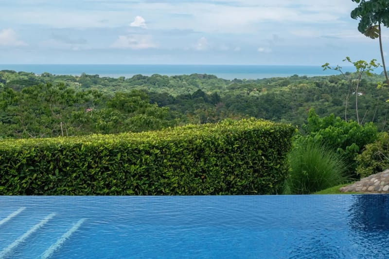 Casa Hacienda Jaguar · 40. An infinity pool extends toward the jungle canopy, offering expansive views of the Pacific Ocean under a bright sky.
