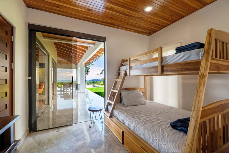 Casa Hacienda Jaguar · 44. This bunk room features a custom wooden bunk bed and a slatted wood ceiling, with a large glass door opening to a terrace offering natural light and views of the pool, jungle, and ocean.