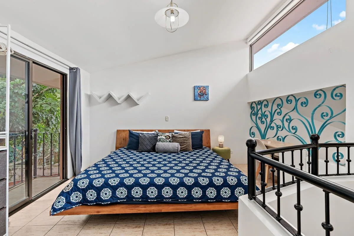 A bedroom with a bed covered in a blue patterned bedspread.