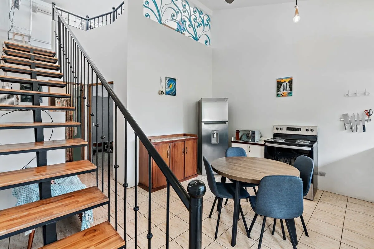 A kitchen and dining area with a table beside the staircase.