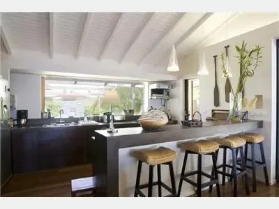 Una cocina moderna con una barra larga y varios taburetes.