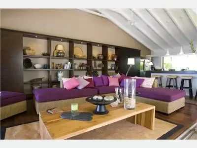 Una sala de estar con asientos morados alrededor de una mesa de centro baja de madera.