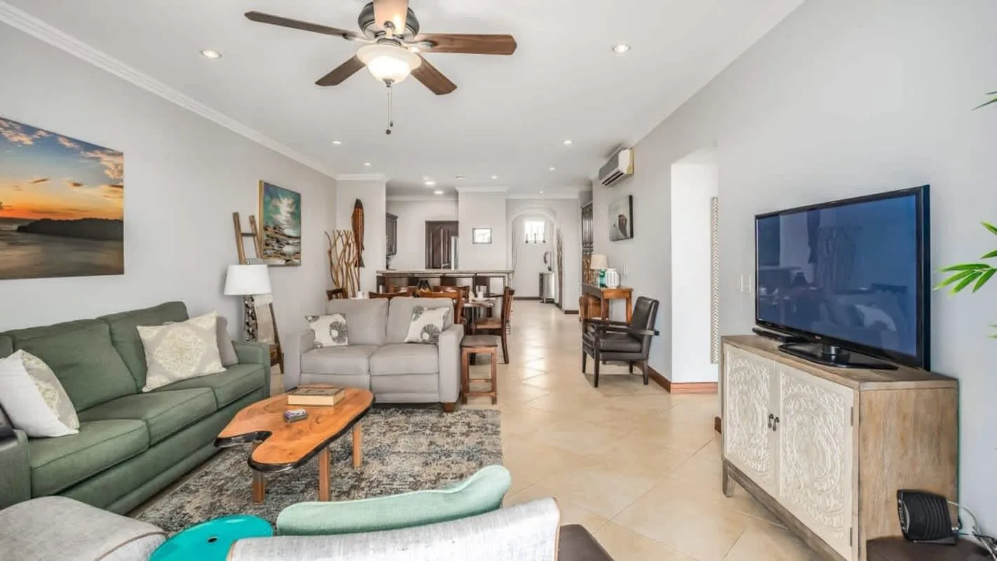 A bright living room with seating, a coffee table, and a television.