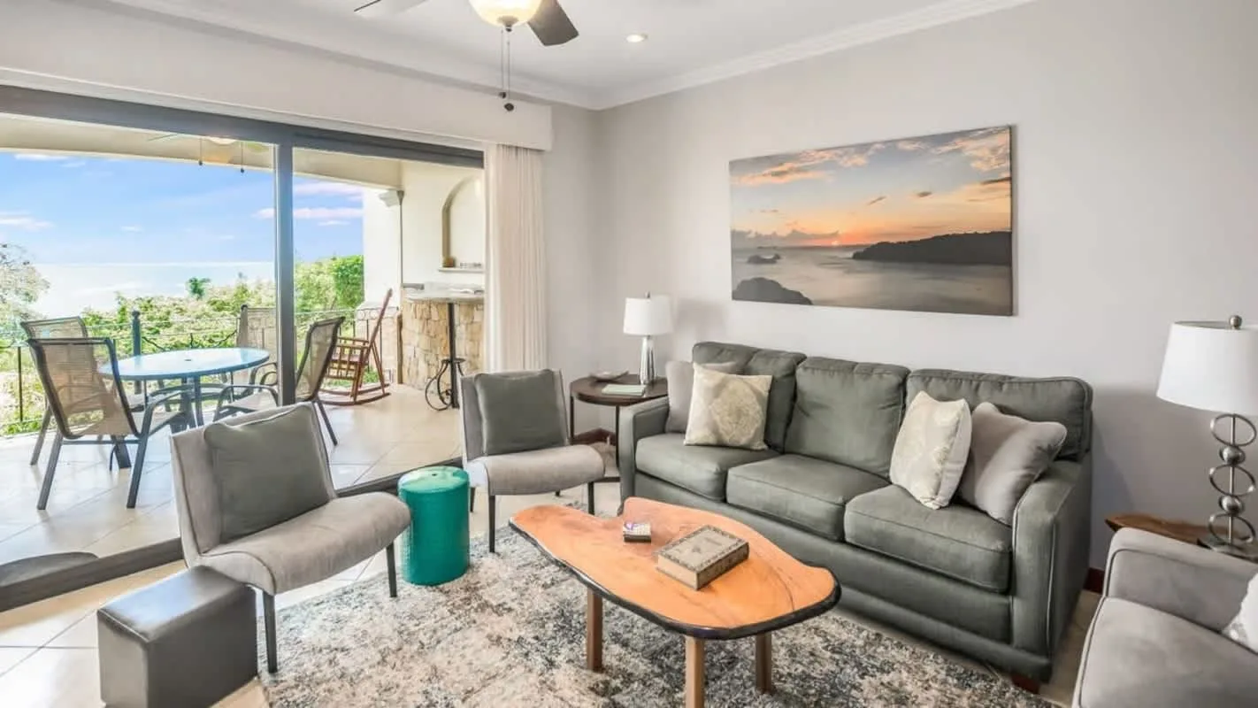 A living room with gray seating, a coffee table, and a view of the patio.