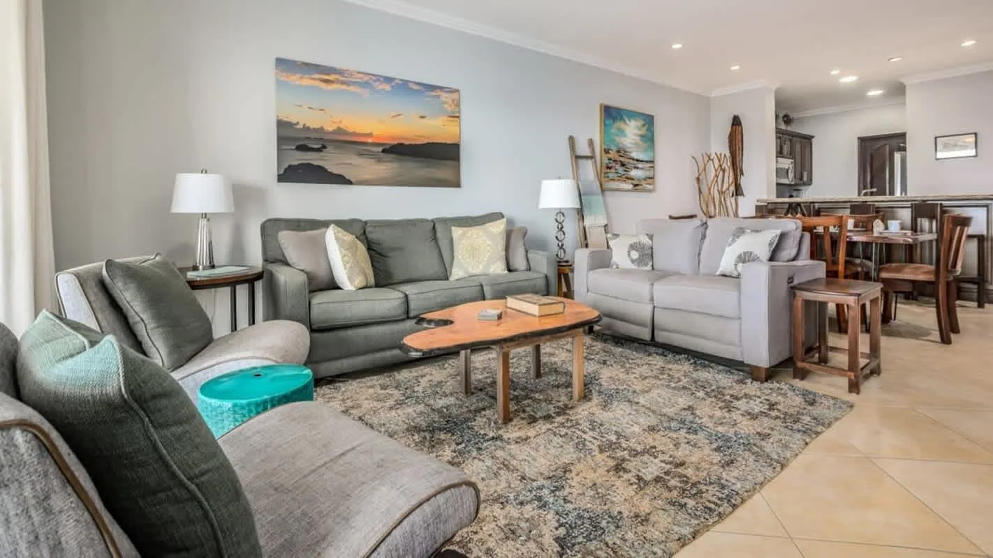 A living room with seating around a coffee table and a dining area beyond.