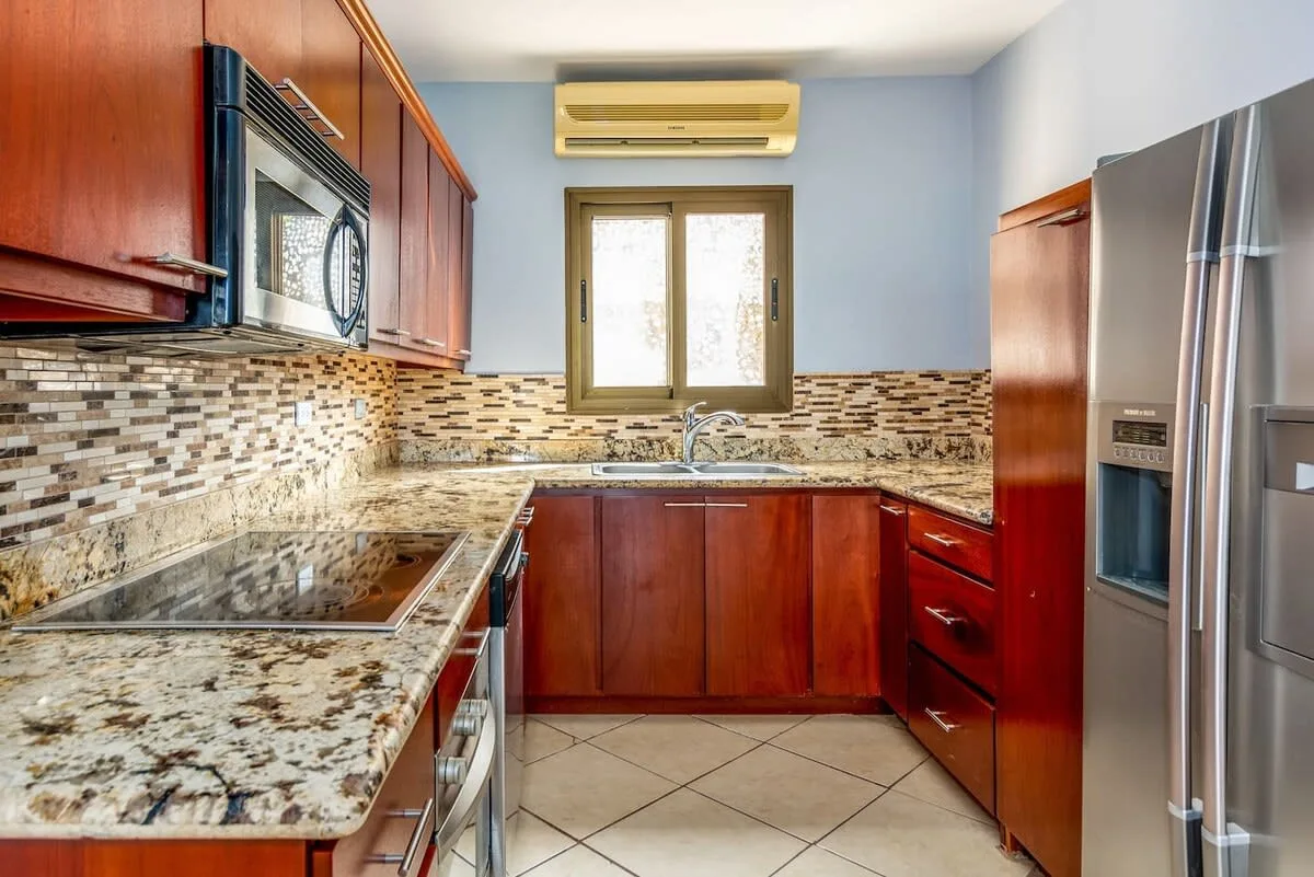 A kitchen with wooden cabinetry, a countertop, and a window above the sink.