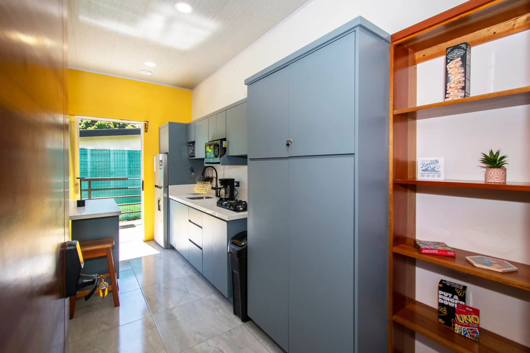 Una cocina compacta con gabinetes grises, una encimera y estantes de madera abiertos.