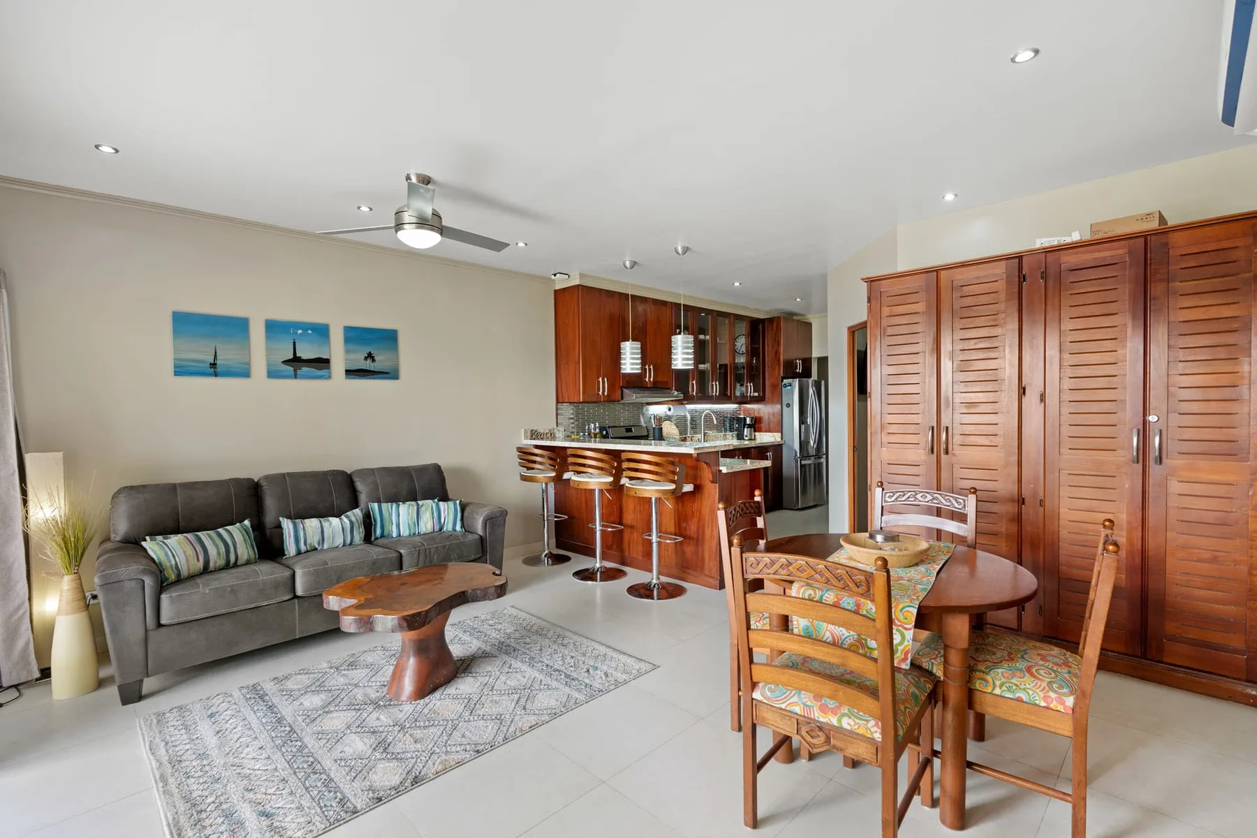 An open-plan living and dining area with a sofa, dining table, and kitchen bar.