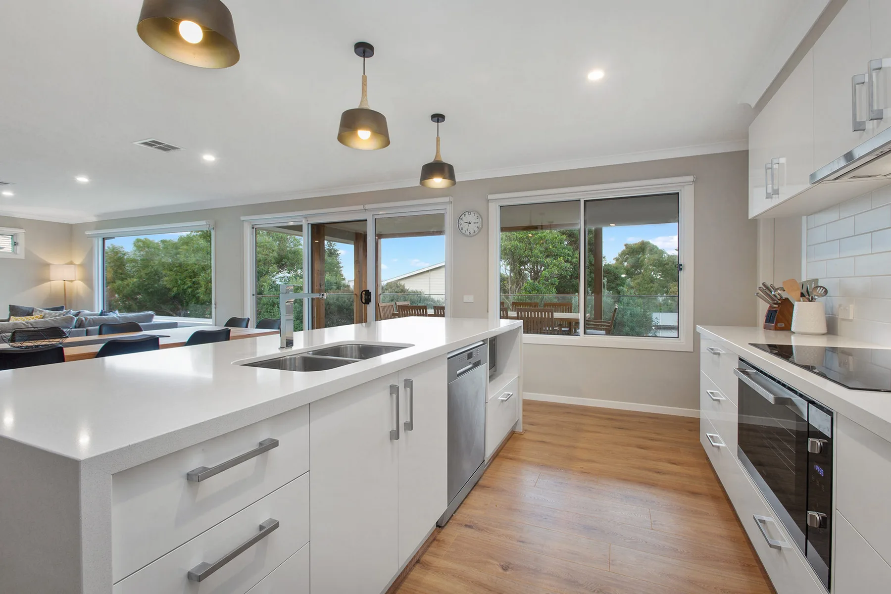 A bright kitchen with white countertops and large windows overlooking greenery.