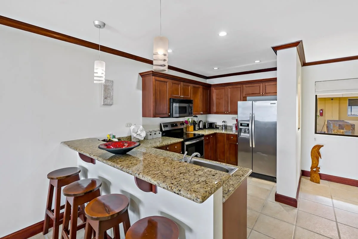 A kitchen with wooden cabinets, stainless steel appliances, and a breakfast bar.