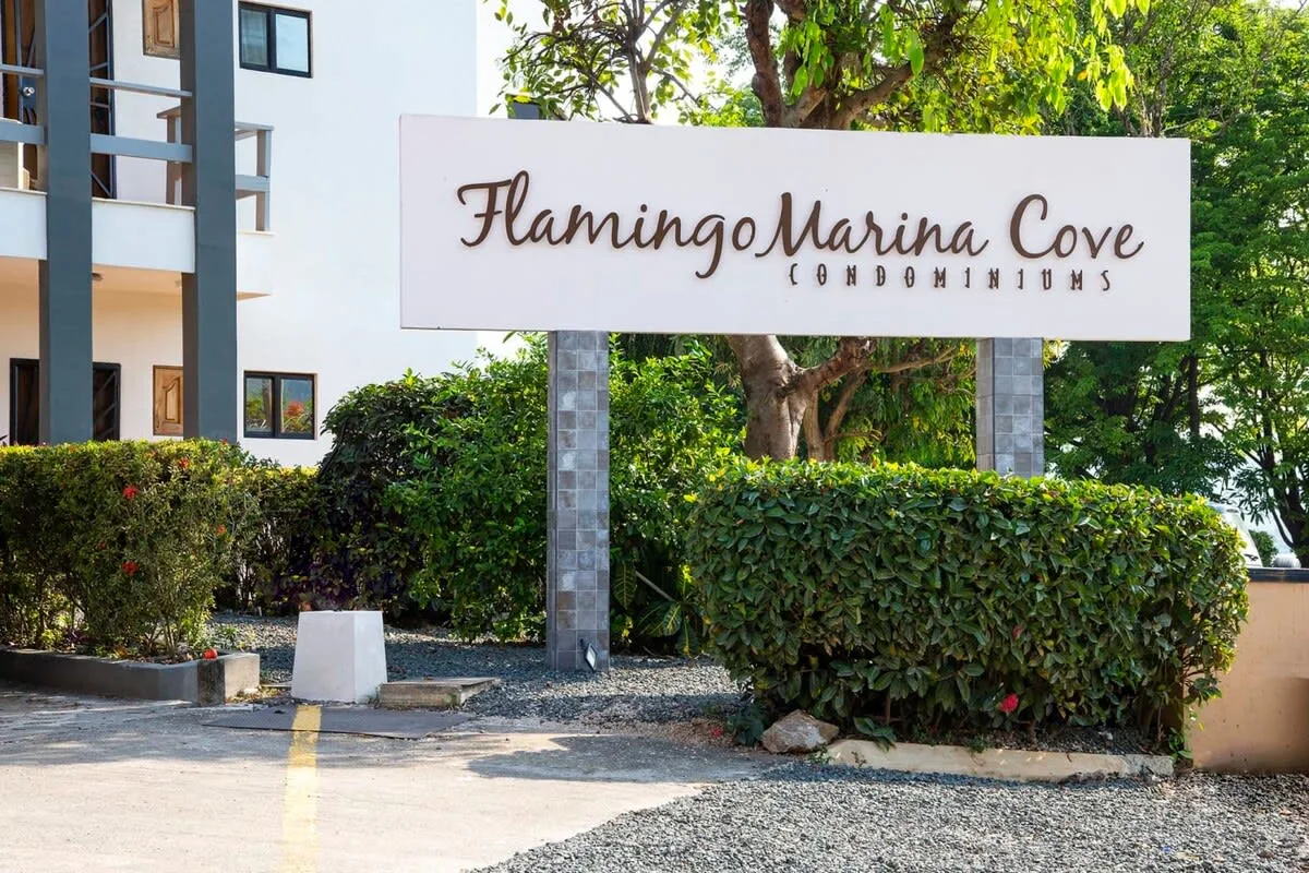 A condominium entrance sign stands beside a landscaped driveway.