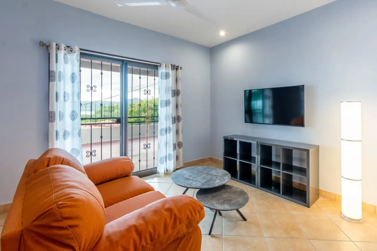 A living room with orange seating, a television, and a round coffee table.