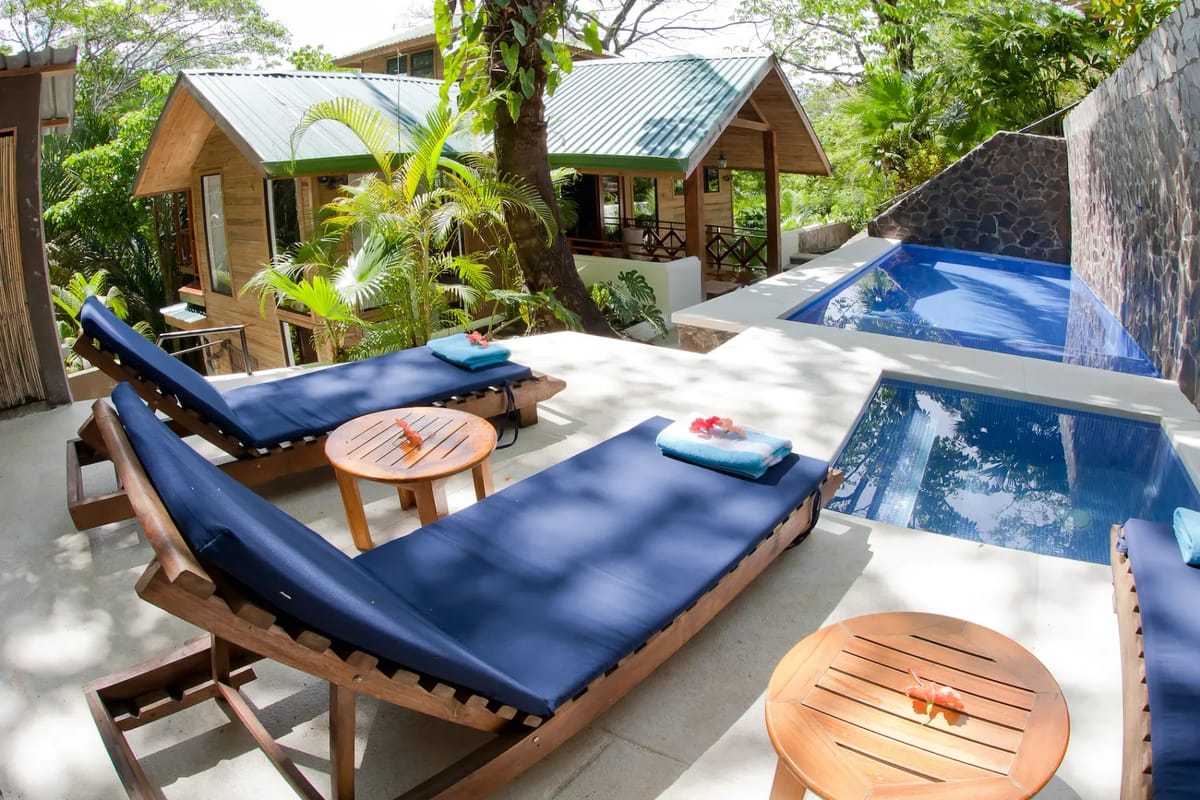 Bali Tree House · 2. A sunlit terrace with lounge chairs and a private pool and jacuzzi provides views of the wooden villa and lush tropical jungle.