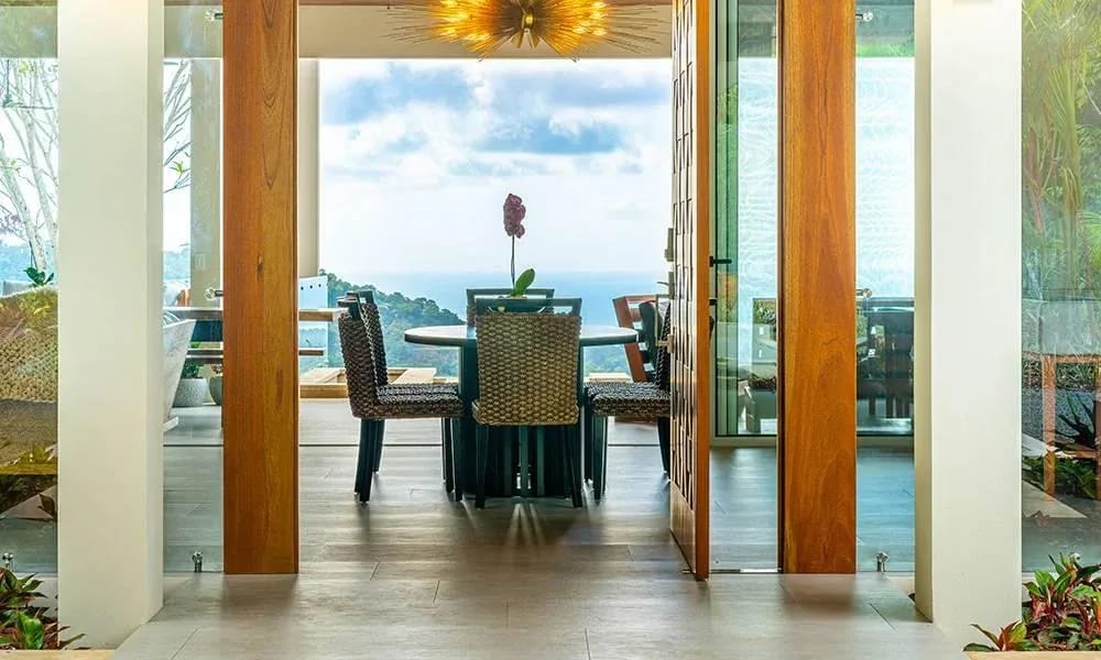 Casa Grande del Mar · 11. An open dining area with a circular table and woven chairs provides expansive views of the Pacific Ocean and surrounding tropical landscape.