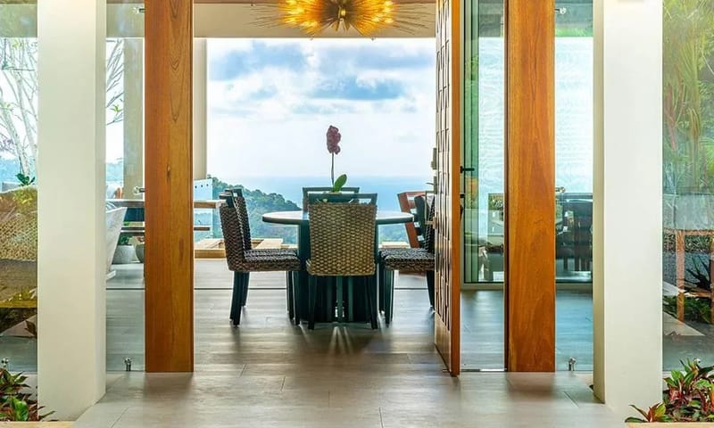 Casa Grande del Mar · 11. An open dining area with a circular table and woven chairs provides expansive views of the Pacific Ocean and surrounding tropical landscape.