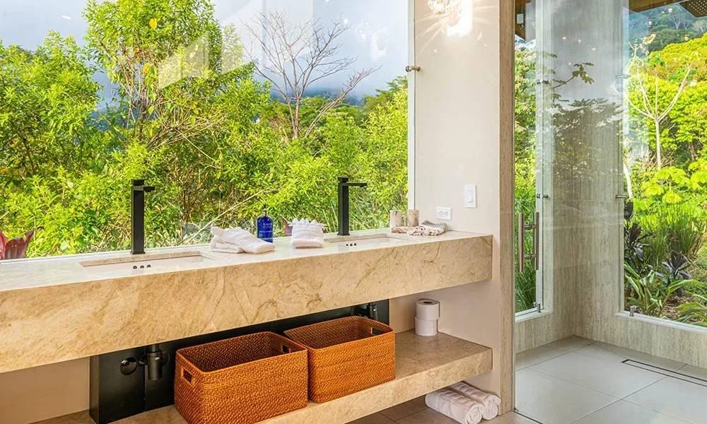 Casa Grande del Mar · 3. The bathroom features a stone vanity and large windows offering views of the surrounding jungle and filling the space with natural light.