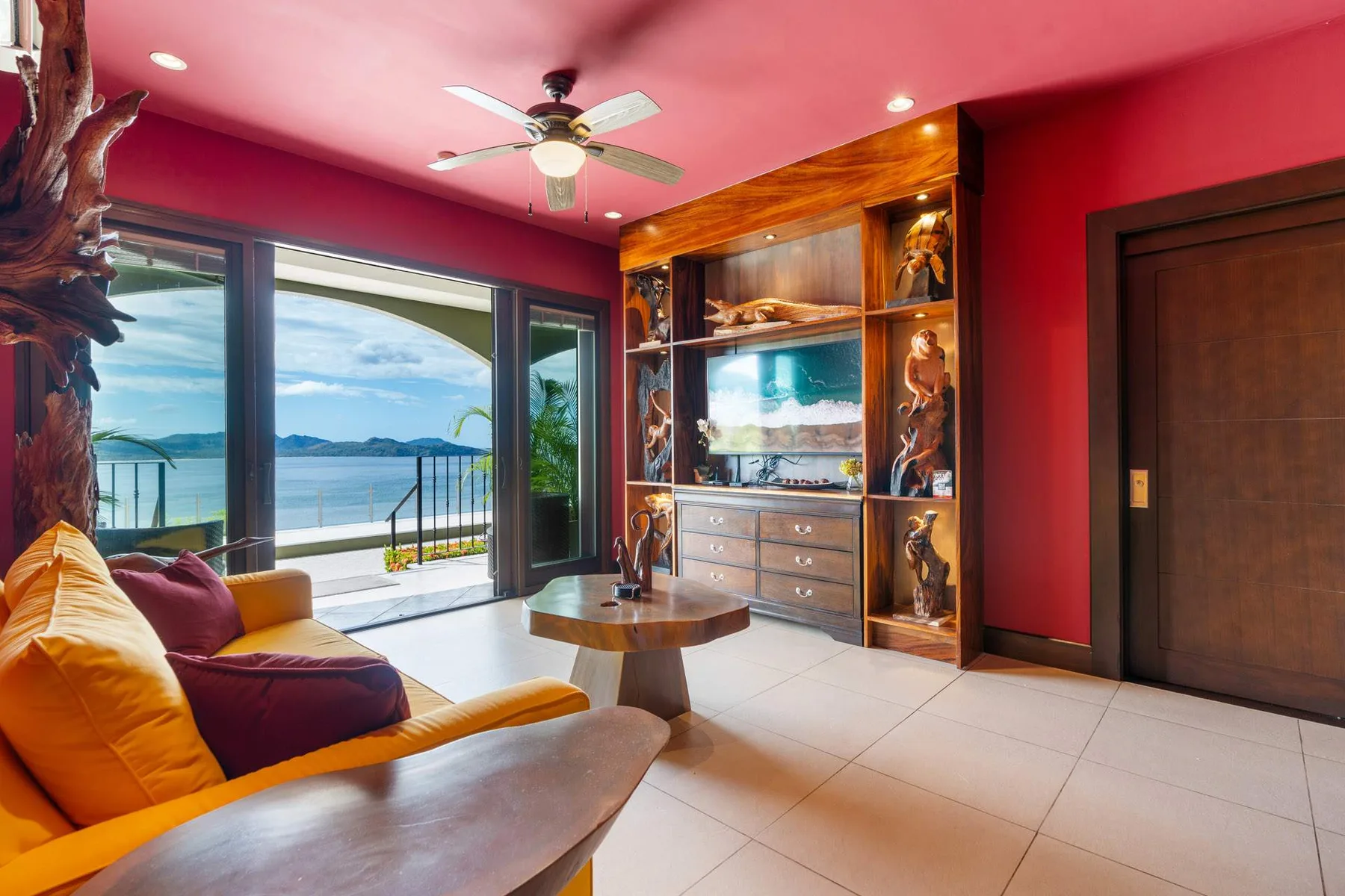 A colorful living room with a display cabinet and sliding glass doors overlooking the water.