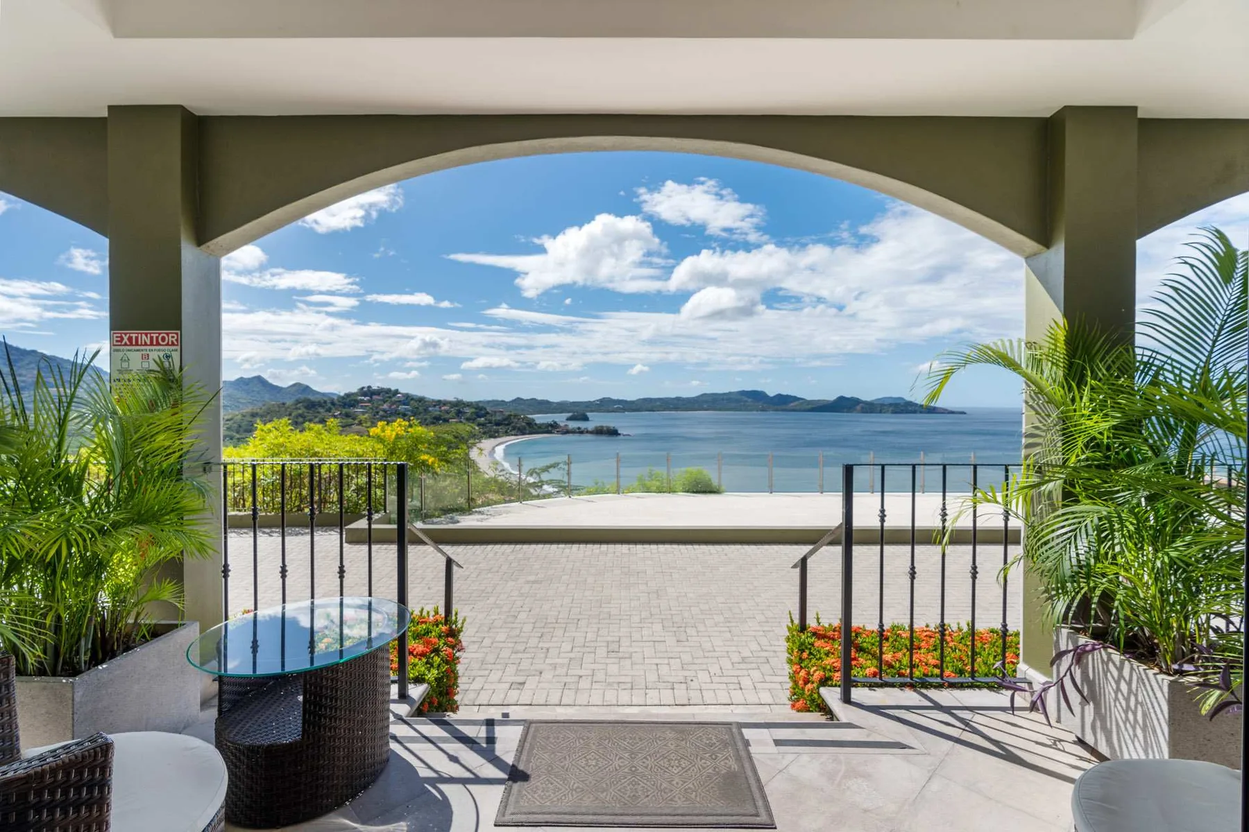 A covered terrace opens onto a paved area overlooking the water.