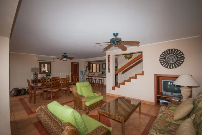 A living and dining area with green seating and a staircase.