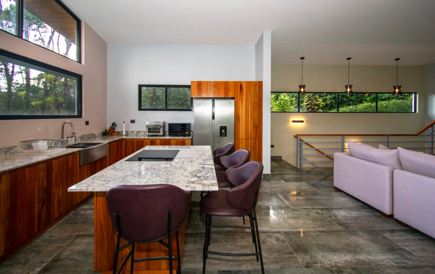 An open-plan kitchen and living area with a marble island and seating.