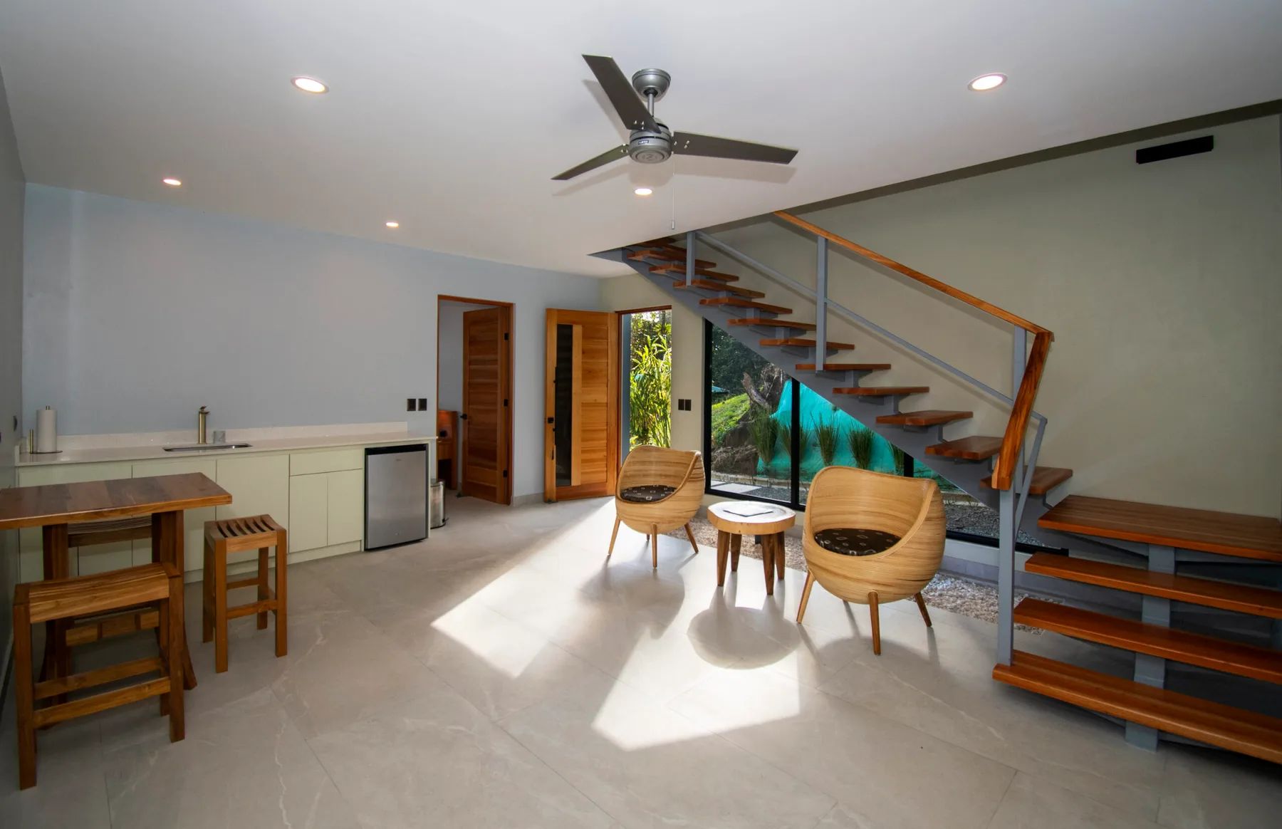 Una habitación luminosa y abierta con una encimera, asientos y una escalera.