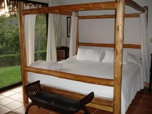 A bedroom with a white bed beneath a wooden canopy frame.