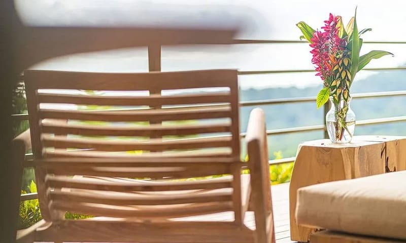 Casa Frenchie & Guest House · 35. The outdoor terrace features wooden lounge furniture, vibrant tropical flowers, and expansive natural views.