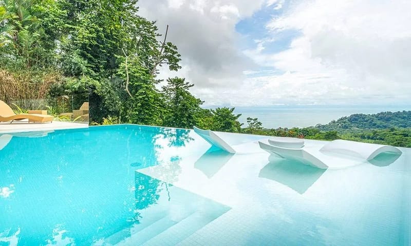 Casa Frenchie & Guest House · 34. This infinity pool, featuring in-water loungers and a poolside terrace, offers an expansive, bright space with panoramic views of the ocean and lush jungle.