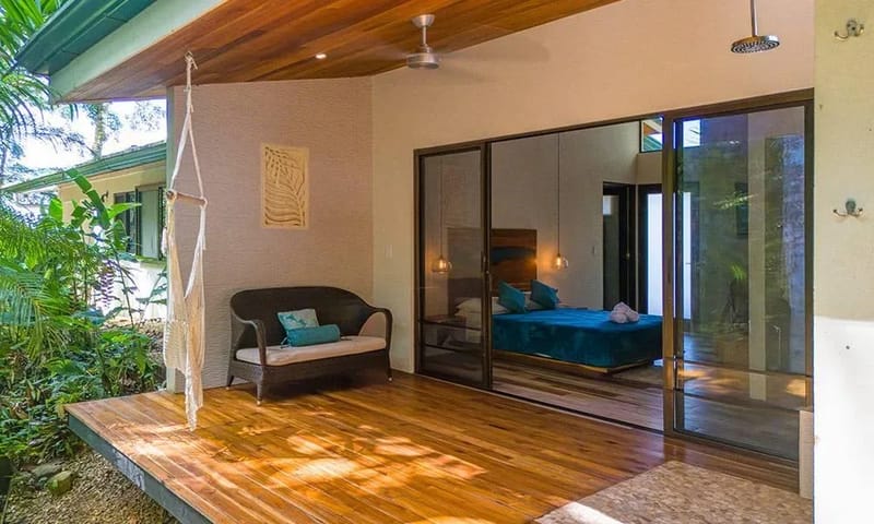 Casa Frenchie & Guest House · 2. A bright bedroom suite features large glass doors opening to a private wooden terrace with jungle views and an outdoor rain shower.