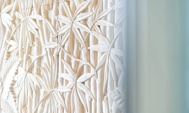 Casa Frenchie & Guest House · 19. The interior space features a carved relief panel depicting bamboo and tropical foliage, naturally lit by light filtering from a nearby window.