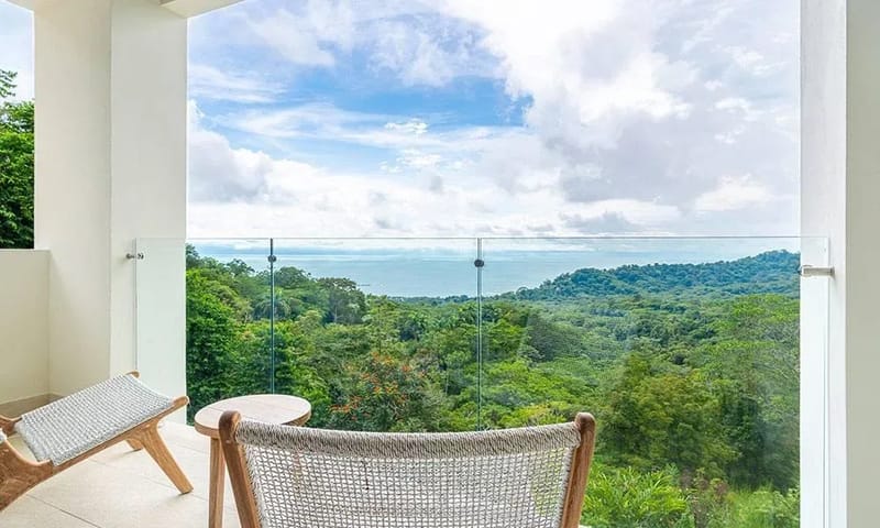 Casa Frenchie & Guest House · 32. This private balcony features a glass railing, providing abundant natural light and expansive views of the jungle and ocean beyond.