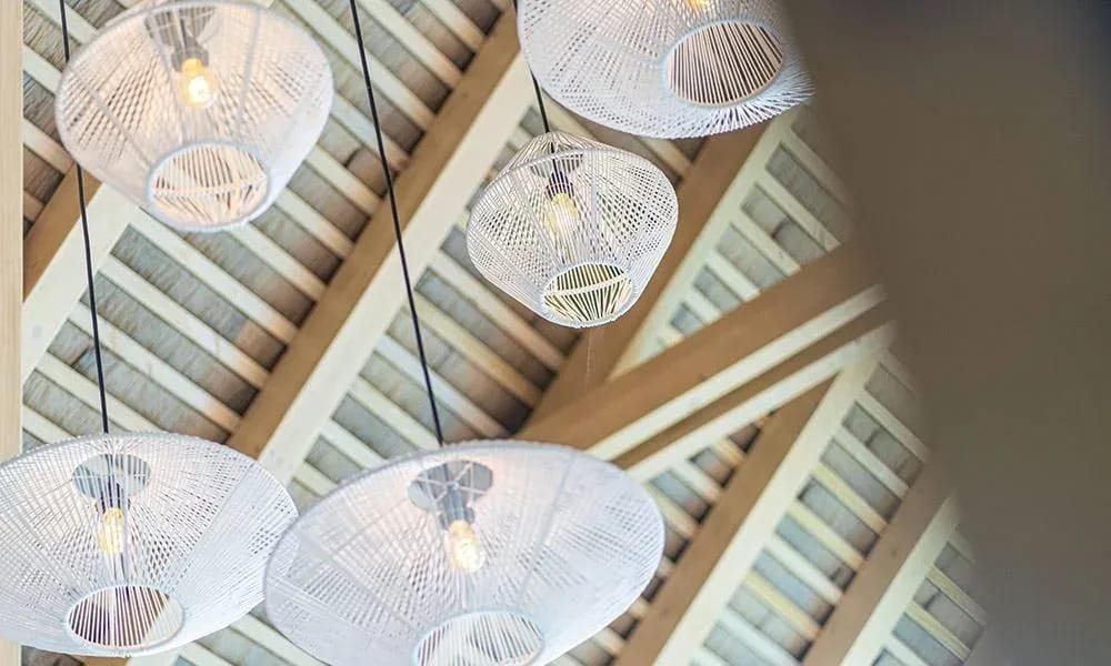Casa Frenchie & Guest House · 5. The high vaulted ceiling with exposed wooden beams is accented by several woven pendant lights, contributing to a spacious and organic feel.
