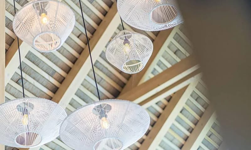 Casa Frenchie & Guest House · 5. The high vaulted ceiling with exposed wooden beams is accented by several woven pendant lights, contributing to a spacious and organic feel.