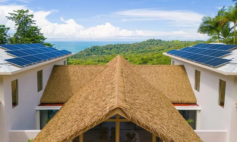 Casa Frenchie & Guest House · 7. This property combines a distinct thatched roof with modern white roof sections and solar panels, enjoying abundant natural light and a sweeping view of the jungle and distant ocean.